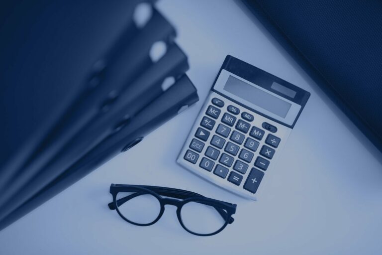 Calculadora, gafas y carpetas de contabilidad sobre la mesa